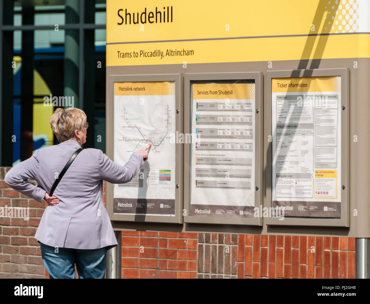 Donna di mezza età cercando confuso nella pianificazione del viaggio su un tram Metrolink a Shudehill in Manchester Foto Stock