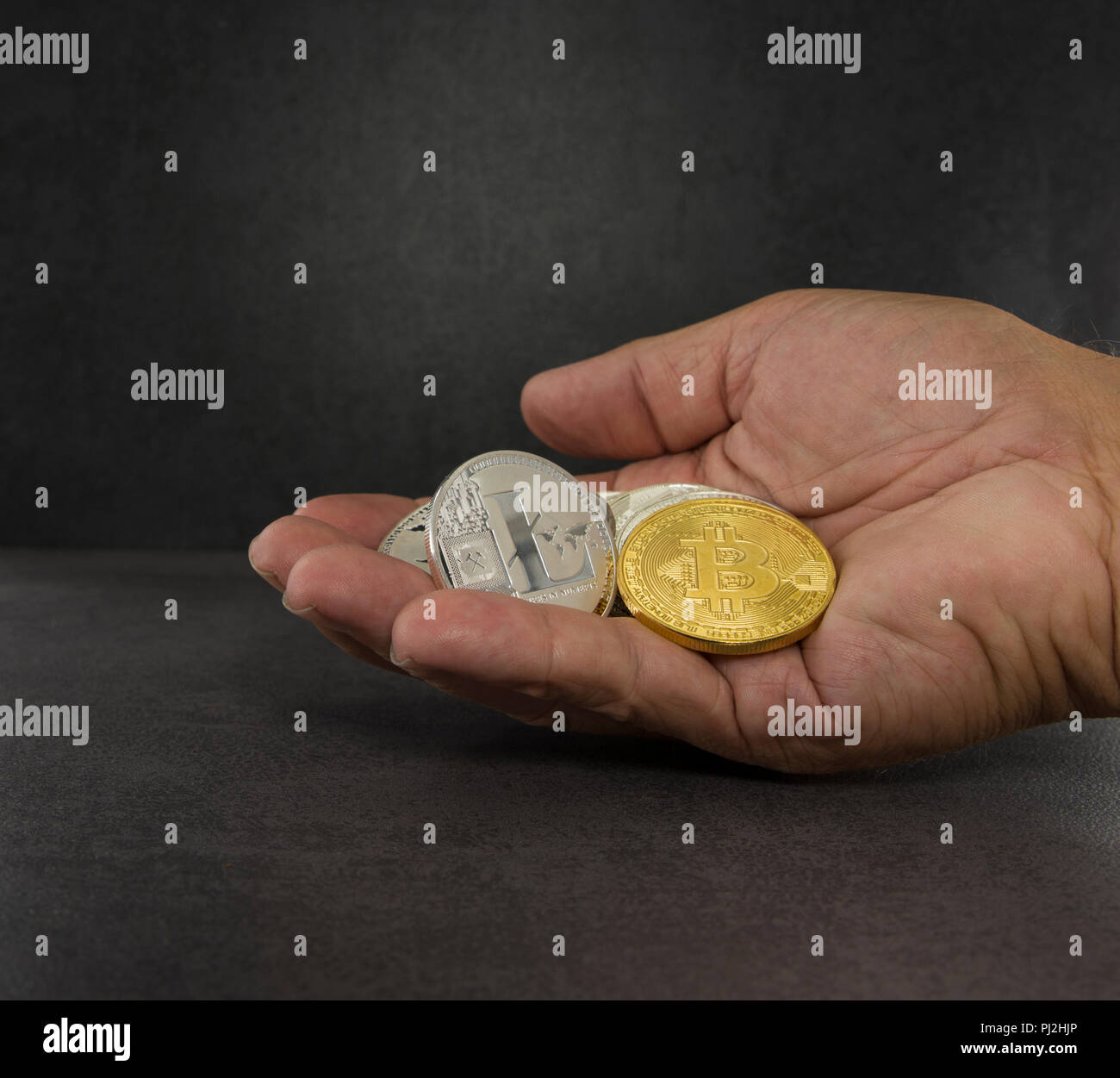 Mano con bitcoin litecoin e altre monete virtuali con sfondo nero Foto Stock