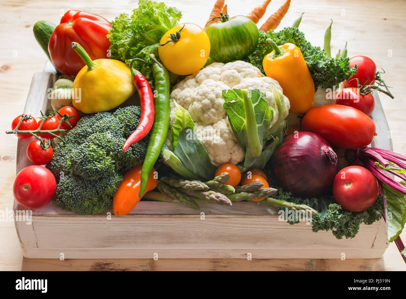 Fresche biologiche verdure colorate in un vassoio bianco su legno tabella di pino, vicino il fuoco selettivo Foto Stock