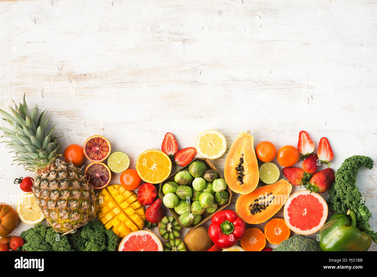 Frutta e verdura ricca di vitamina C, Arance Pompelmi mango kiwi Kale pepe al limone Ananas Papaia cavoli broccoli, su legno tavolo bianco, vista dall'alto, copia di spazio, il fuoco selettivo Foto Stock