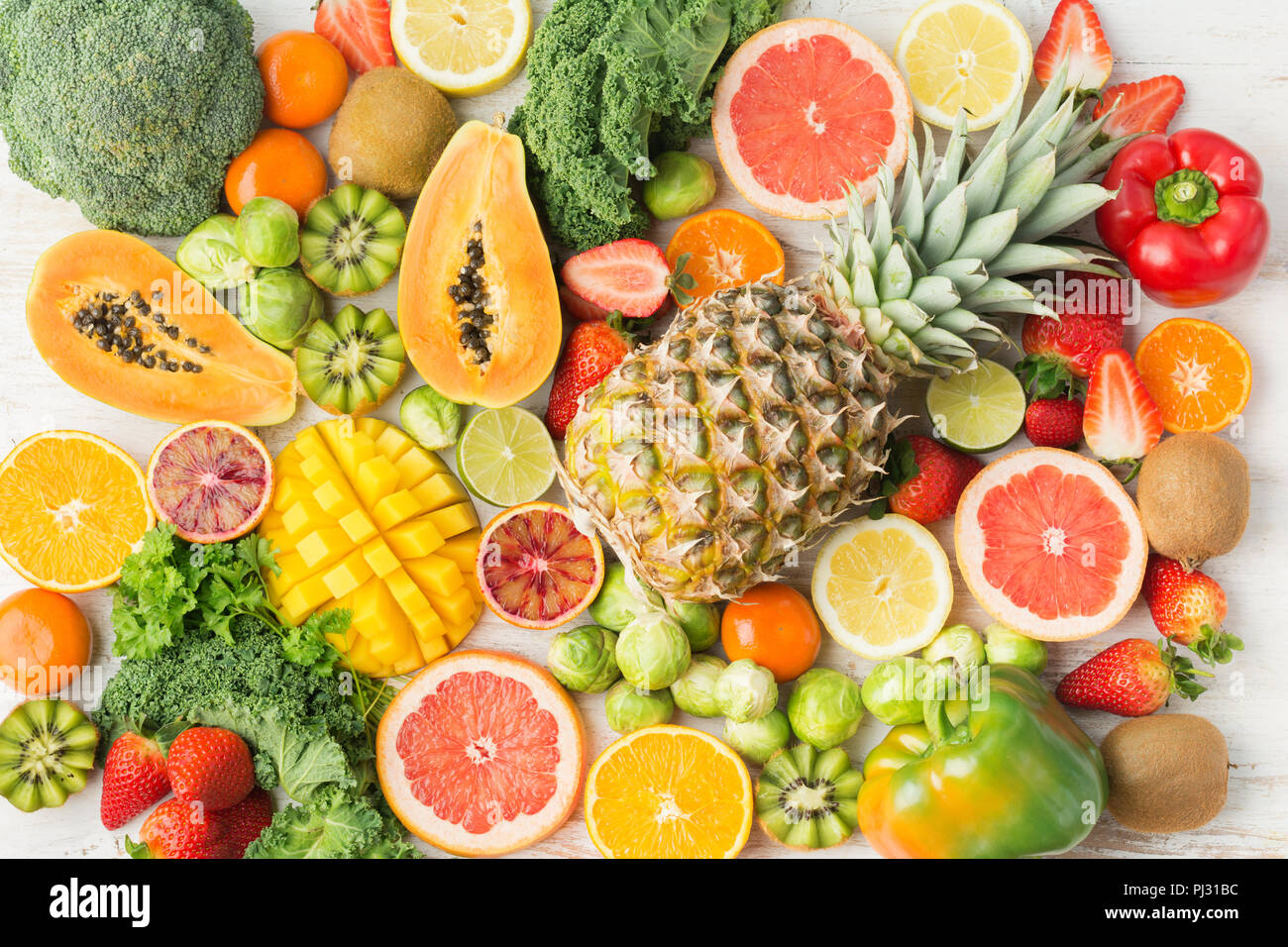 Frutta e verdura ricca di vitamina C la configurazione di sfondo, Arance Pompelmi mango kiwi Kale pepe al limone Ananas Papaia cavoli broccoli, sul tavolo bianco, vista dall'alto, il fuoco selettivo Foto Stock