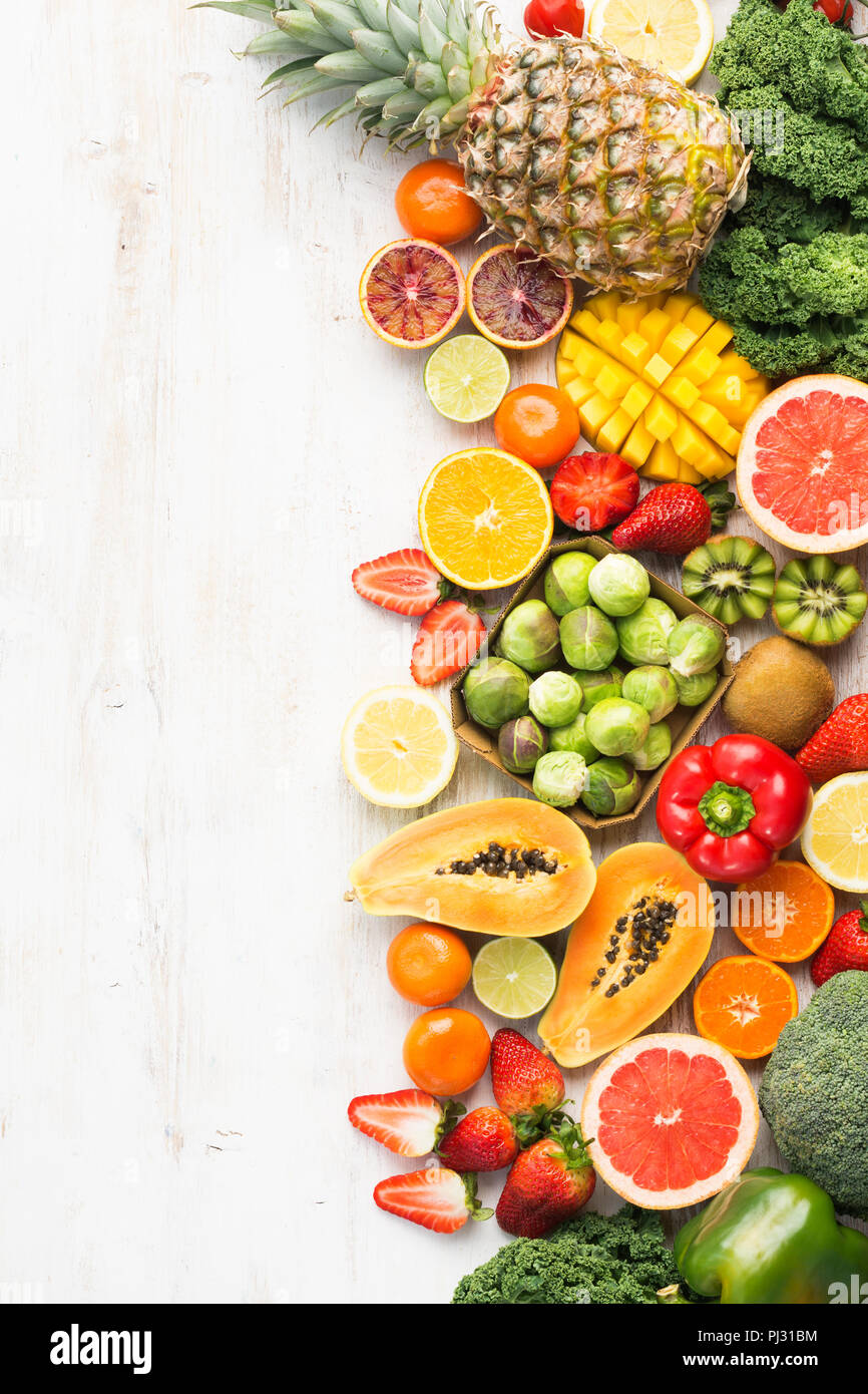 Frutta e verdura ricca di vitamina C, Arance Pompelmi mango kiwi Kale pepe al limone Ananas Papaia cavoli broccoli, sul tavolo bianco, vista dall'alto, copiare lo spazio per testo, verticale, il fuoco selettivo Foto Stock