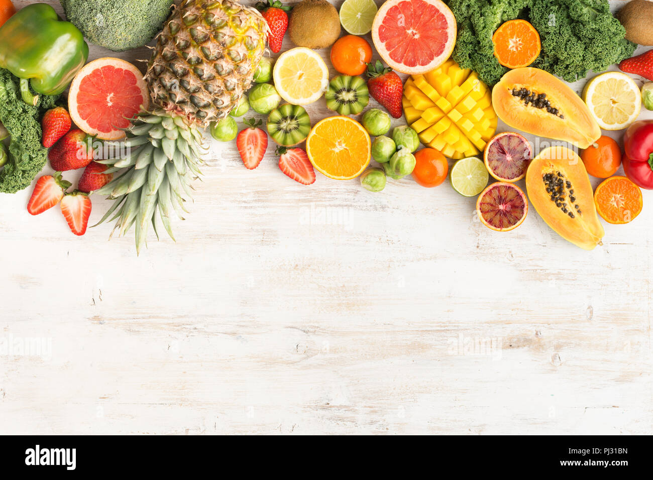 Frutta e verdura ricca di vitamina C, Arance Pompelmi mango kiwi Kale pepe al limone Ananas Papaia cavoli broccoli, su legno tavolo bianco, vista dall'alto, copia di spazio, il fuoco selettivo Foto Stock