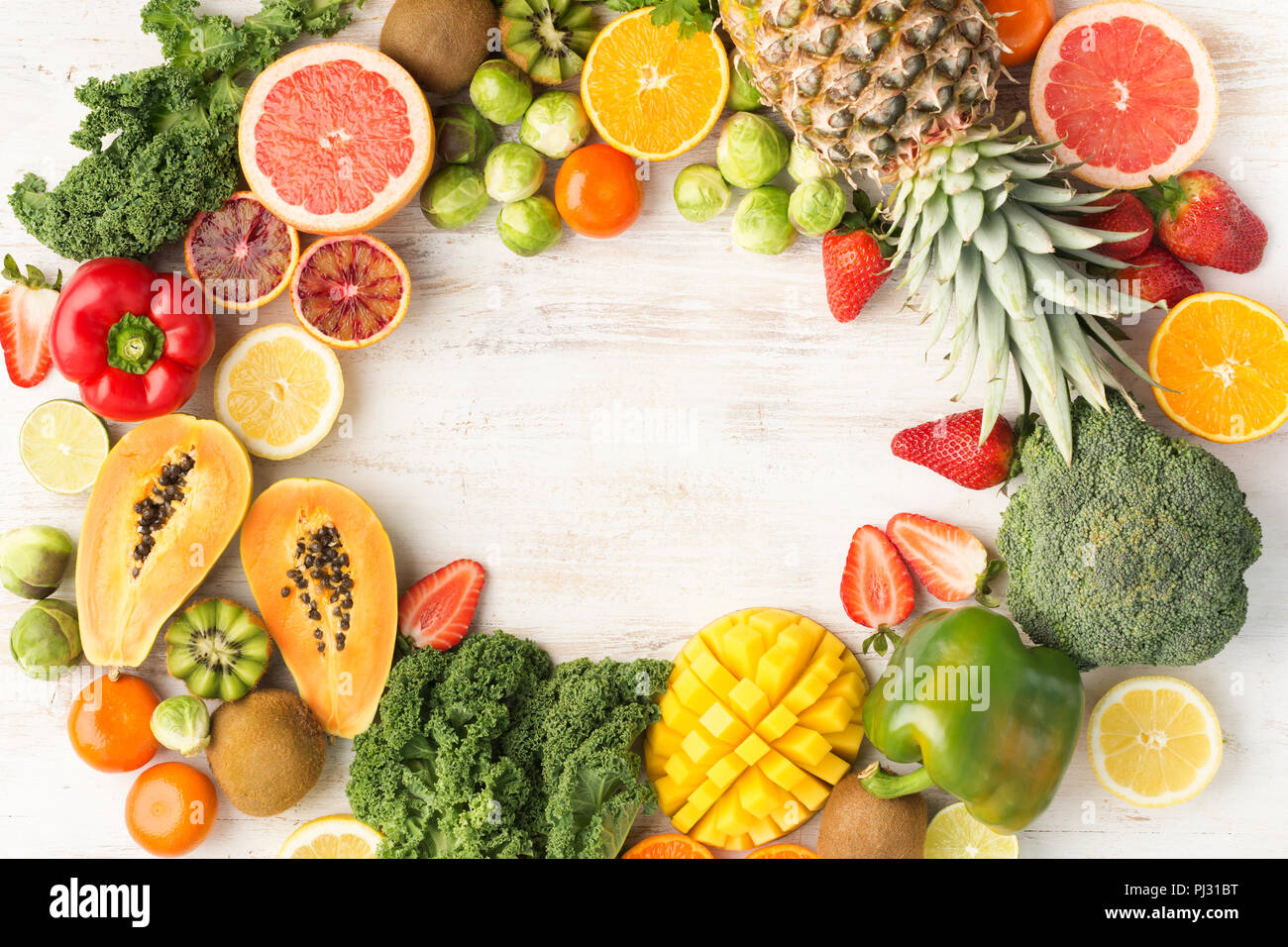 Telaio di frutta e verdura ricca di vitamina C, Arance Pompelmi mango kiwi Kale pepe al limone Ananas Papaia cavoli broccoli, su legno tavolo bianco, vista dall'alto, copia di spazio, il fuoco selettivo Foto Stock