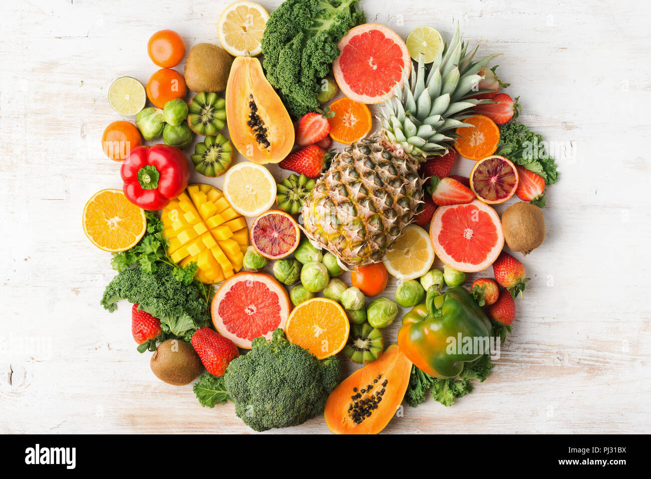Frutta e verdura ricca di vitamina C cerchio di background forma, Arance Pompelmi mango kiwi Kale pepe al limone Ananas Papaia cavoli broccoli, sul tavolo bianco, vista dall'alto, il fuoco selettivo Foto Stock