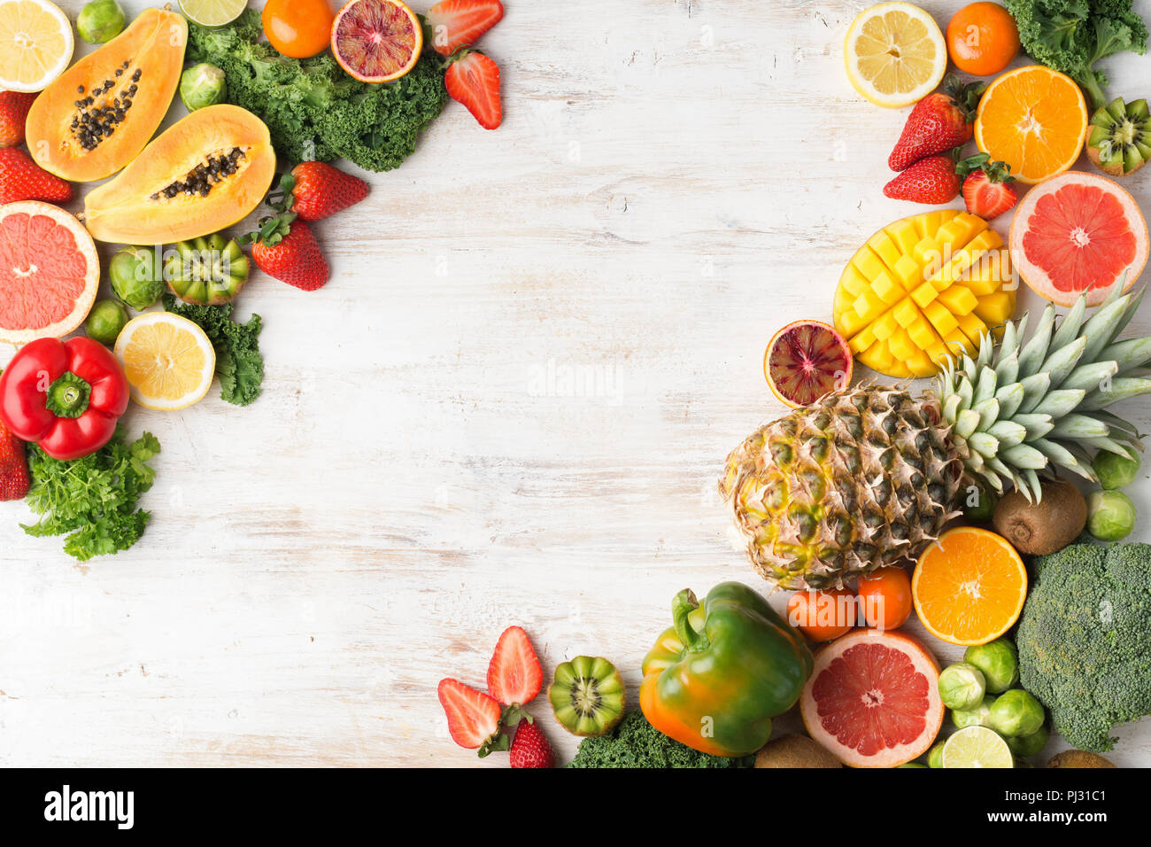 Assortimento di frutta e verdura ricca di vitamina C, copia spazio, Arance Pompelmi mango kiwi Kale pepe al limone Ananas Papaia cavoli broccoli, su legno tavolo bianco, vista dall'alto, il fuoco selettivo Foto Stock