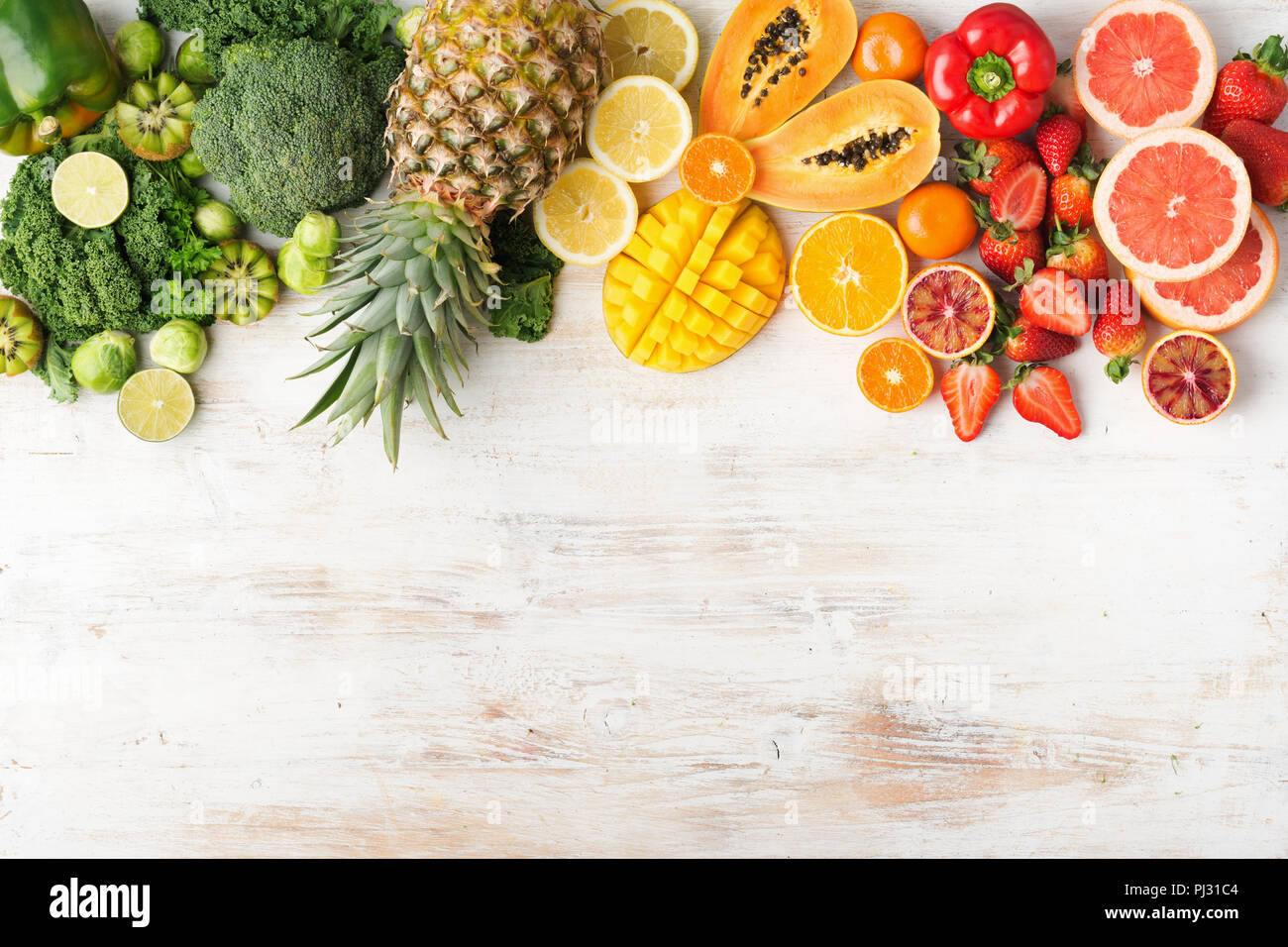 Vista superiore della frutta e della verdura ricca di vitamina C nei colori dell'arcobaleno, Arance Pompelmi mango kiwi Kale pepe al limone Ananas Papaia broccoli, sul tavolo bianco, copiare lo spazio per testo, il fuoco selettivo Foto Stock