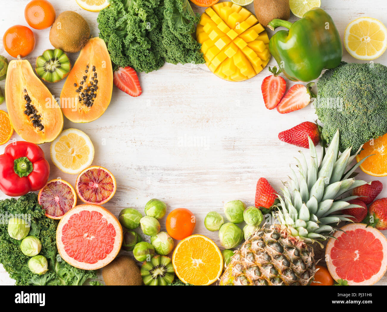 Cornice fatta di frutta e verdura ricca di vitamina C, Arance Pompelmi mango kiwi Kale pepe al limone Ananas Papaia cavoli broccoli, su legno tavolo bianco, vista dall'alto, copia di spazio, il fuoco selettivo Foto Stock