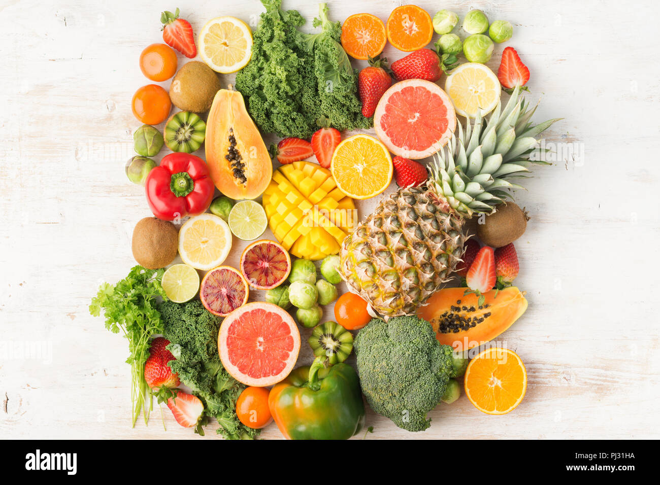 Frutta e verdura ricca di vitamina C la configurazione di sfondo, Arance Pompelmi mango kiwi Kale pepe al limone Ananas Papaia cavoli broccoli, sul tavolo bianco, vista dall'alto, spazio copia messa a fuoco selettiva Foto Stock