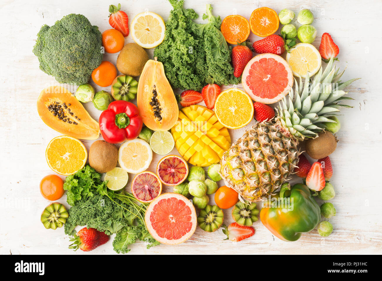 Frutta e verdura ricca di vitamina C disposte nel rettangolo, Arance Pompelmi mango kiwi Kale pepe al limone Ananas Papaia cavoli broccoli, sul tavolo bianco, vista dall'alto, il fuoco selettivo Foto Stock