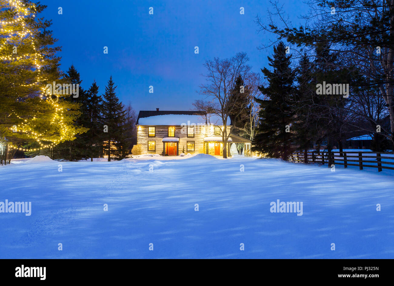 Casa log in una notte d'inverno con le luci accese Foto Stock