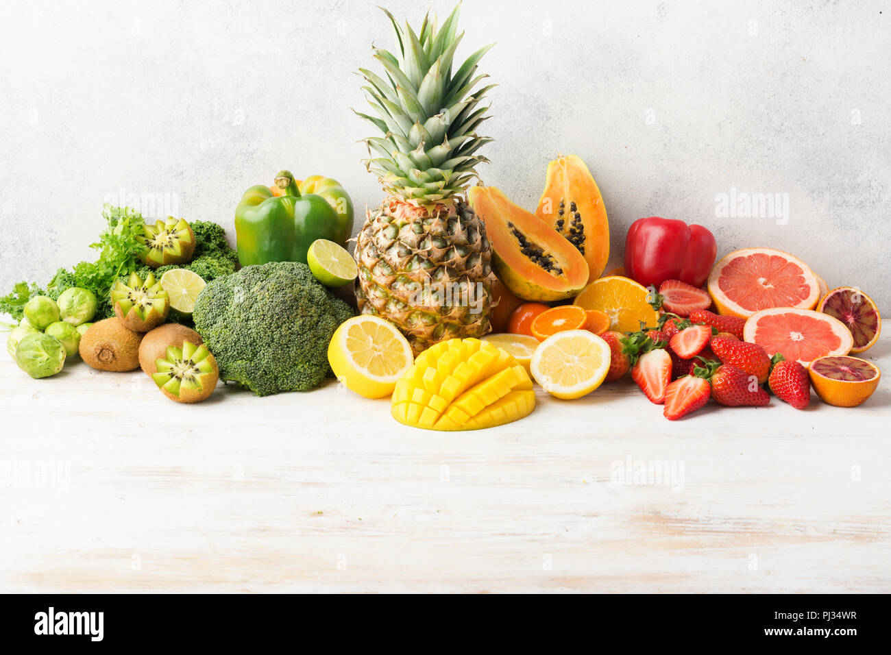 La vitamina C frutta e verdura nei colori dell'arcobaleno, Arance Pompelmi mango kiwi Kale pepe al limone Ananas Papaia broccoli, sul tavolo bianco, copiare lo spazio per testo, il fuoco selettivo Foto Stock