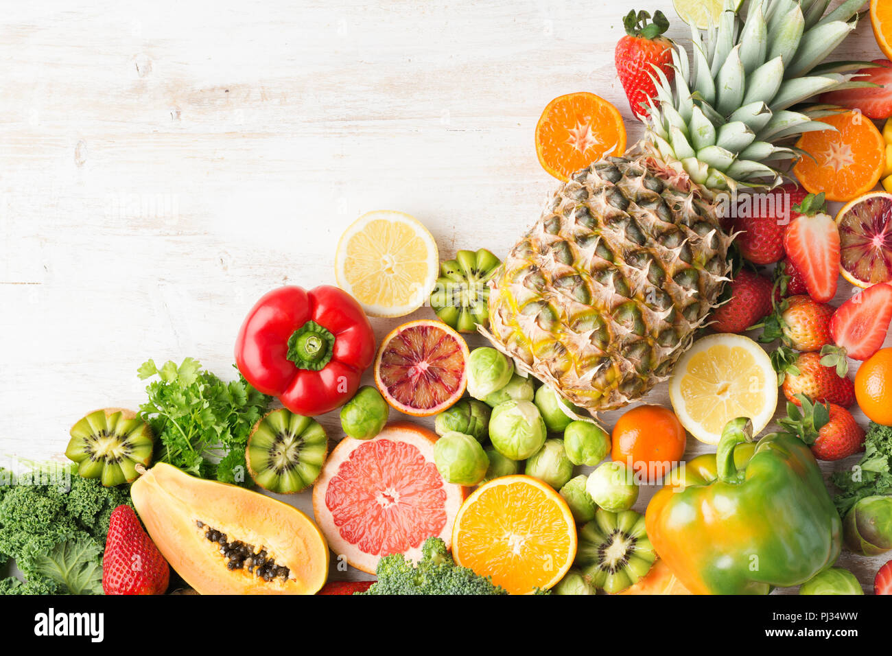 Frutta e verdura ricca di vitamina C disposizione, Arance Pompelmi mango kiwi Kale pepe al limone Ananas Papaia cavoli broccoli, sul tavolo bianco, vista dall'alto, copiare lo spazio per testo, il fuoco selettivo Foto Stock