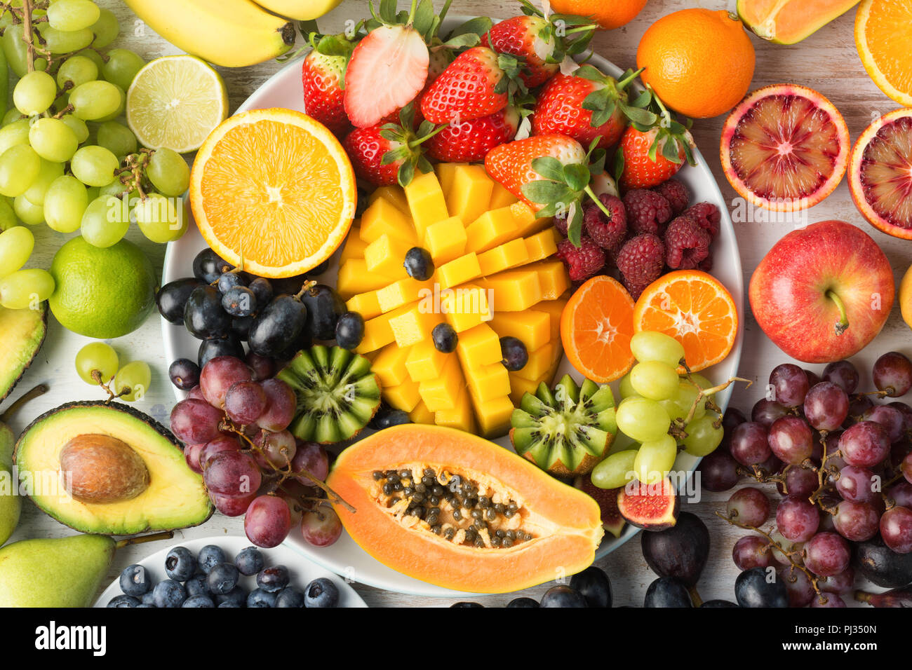 Cibo sano sfondo, assortimento di frutta in arcobaleno di colori sul bianco tabella, vista dall'alto, il fuoco selettivo Foto Stock