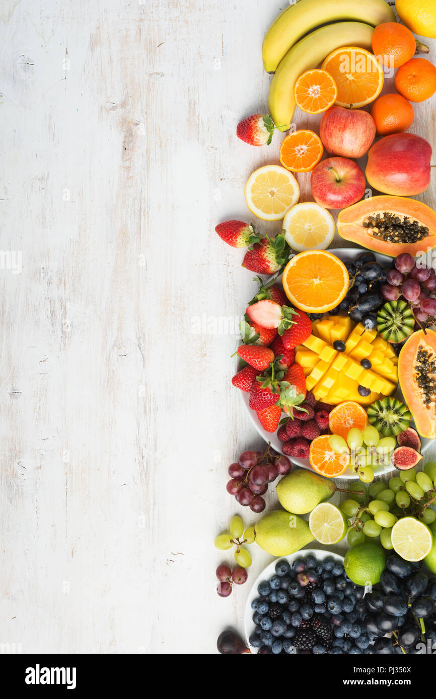 Assortimento di frutta fresca e verdura nei colori dell'arcobaleno sul bianco tavola verticale, vista dall'alto, il fuoco selettivo Foto Stock