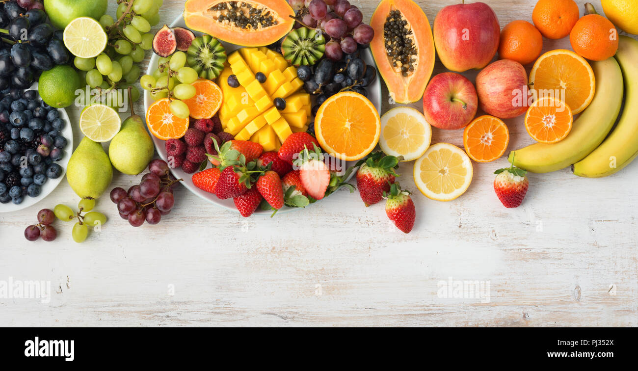 Assortimento di frutta fresca e verdura nei colori dell'arcobaleno sul bianco tabella, vista dall'alto, il fuoco selettivo Foto Stock
