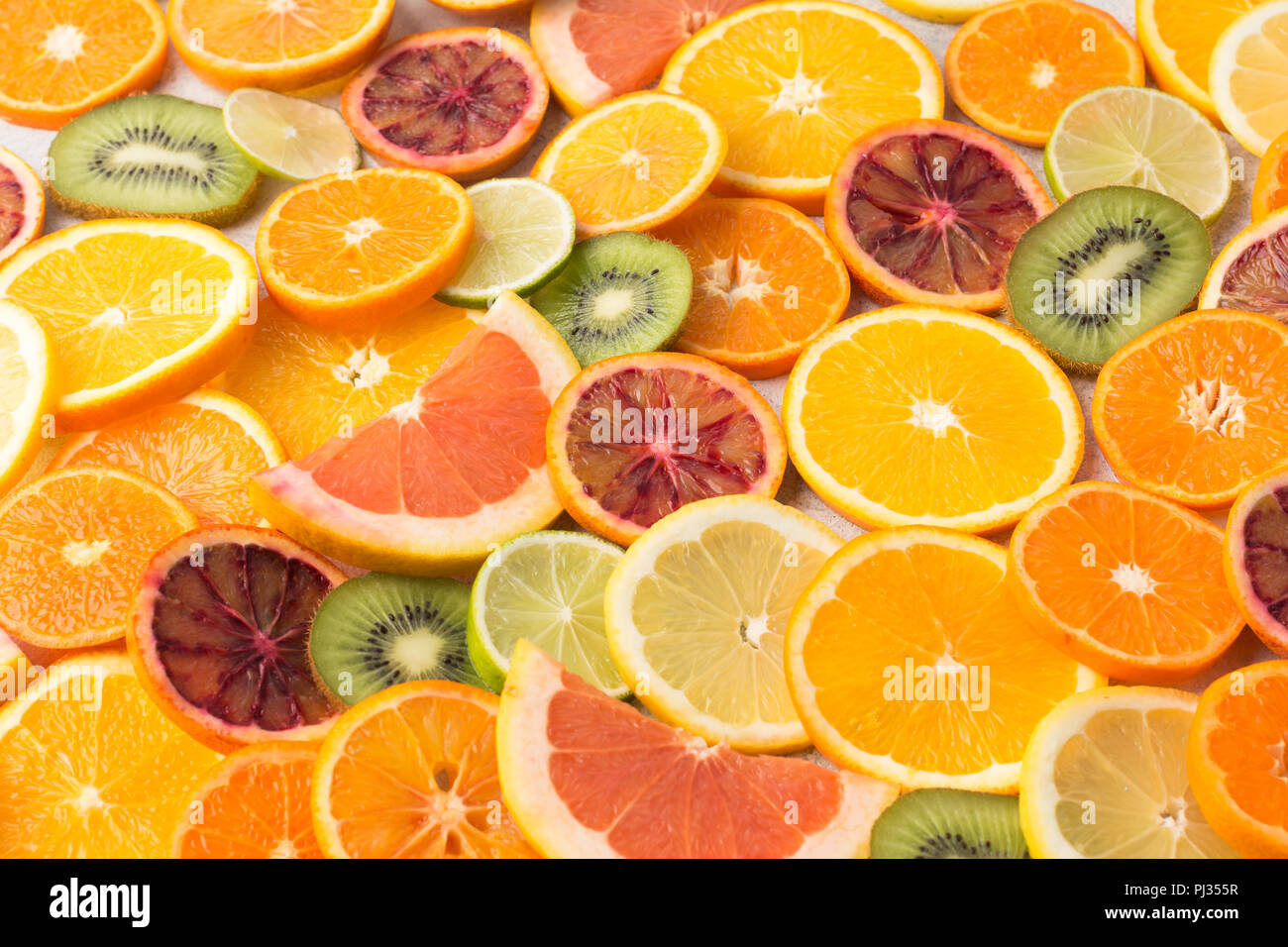 Colorato sfondo frutti Arance, clementine e arance pigmentate, kiwi e pompelmi sul tavolo bianco, il fuoco selettivo Foto Stock