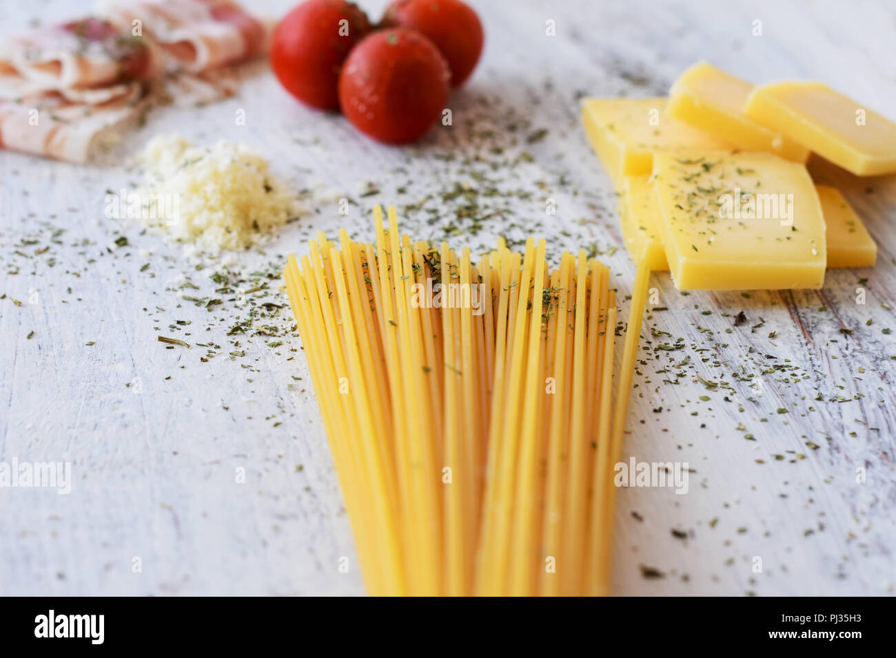 Ingredienti per la cottura- pancetta dolce ciliegie di pomodoro, formaggio, spaghetti-/ di pasta alimentare a sfondo di luce sullo sfondo di legno Foto Stock