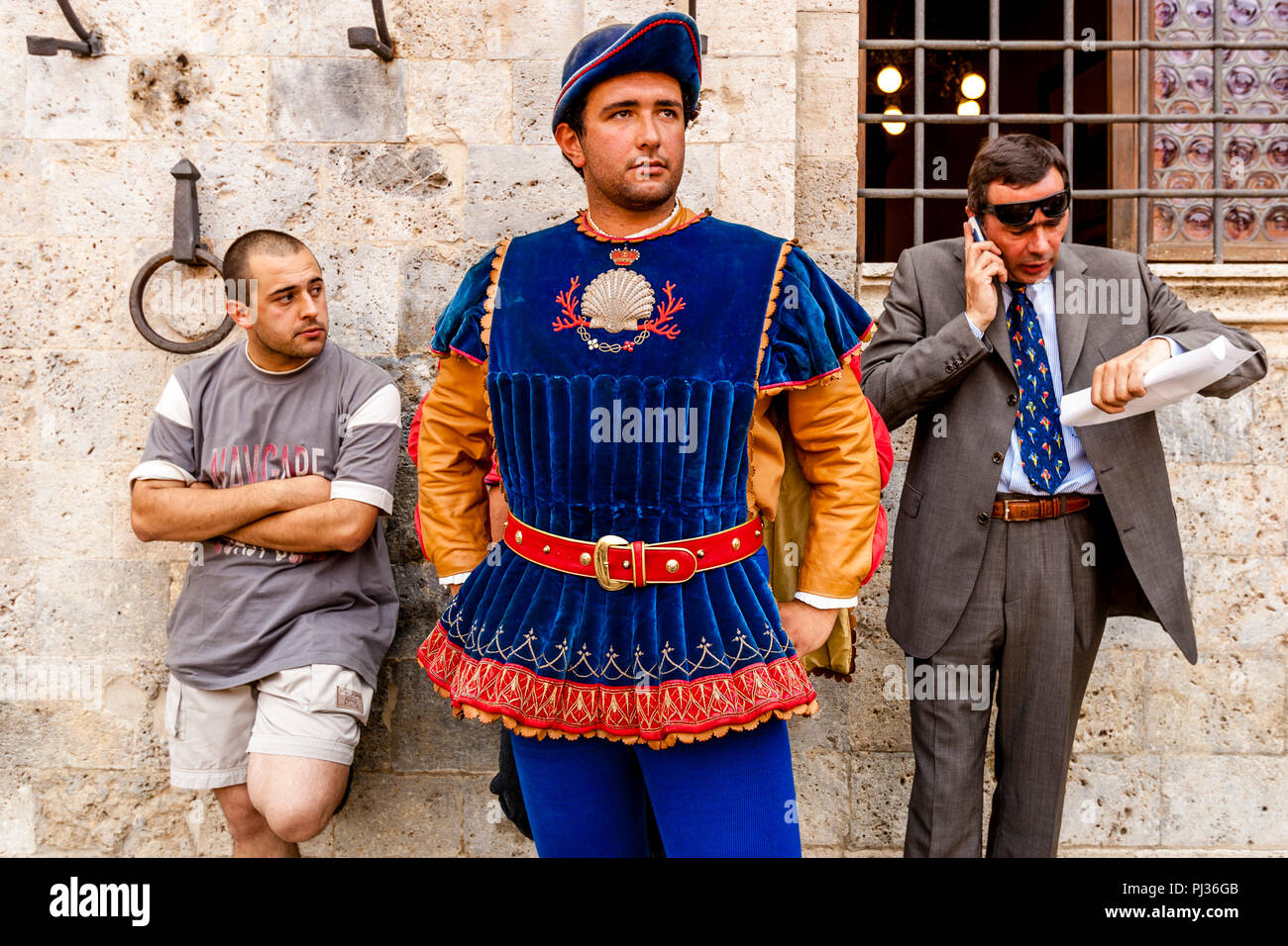 Membri del Nicchio (Shell) Contrada attendere per l'assegnazione dei cavalli cerimonia per iniziare in Piazza del Campo Palio di Siena, Siena, Italia Foto Stock