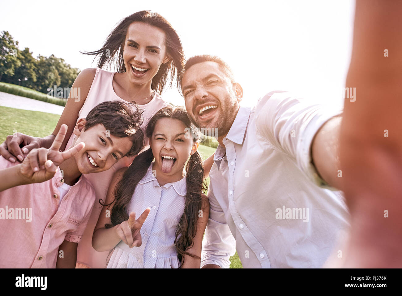 Bei ricordi. Famiglia di quattro tenendo selfie foto su smartp Foto Stock