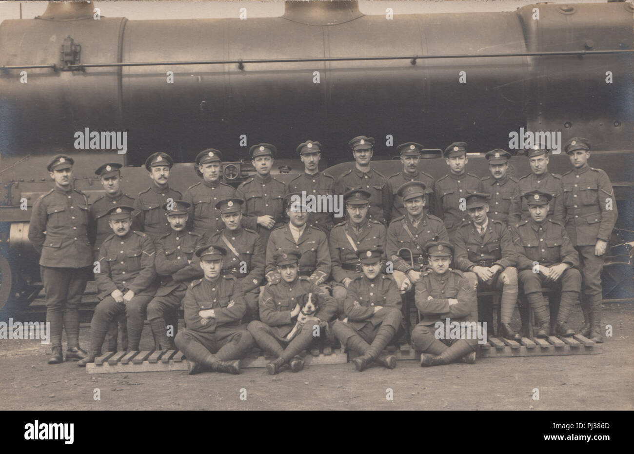 Vintage Fotografia che mostra un gruppo di esercito britannico soldati con un cane in posa di fronte di un treno Foto Stock