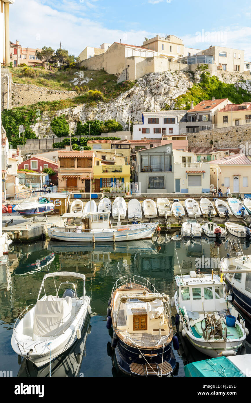 Il piccolo porto del Vallon des Auffes a Marsiglia alla fine della giornata con barche ormeggiate di fronte cabanons colorati e case sotto la scogliera. Foto Stock