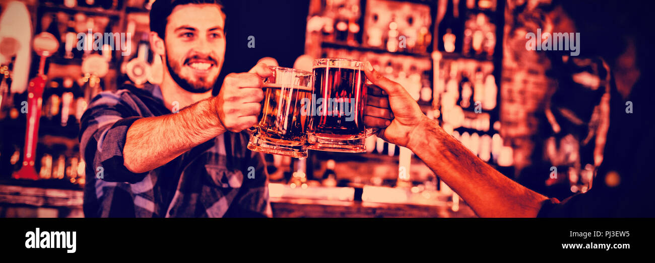 Due giovani uomini tostare i boccali da birra Foto Stock