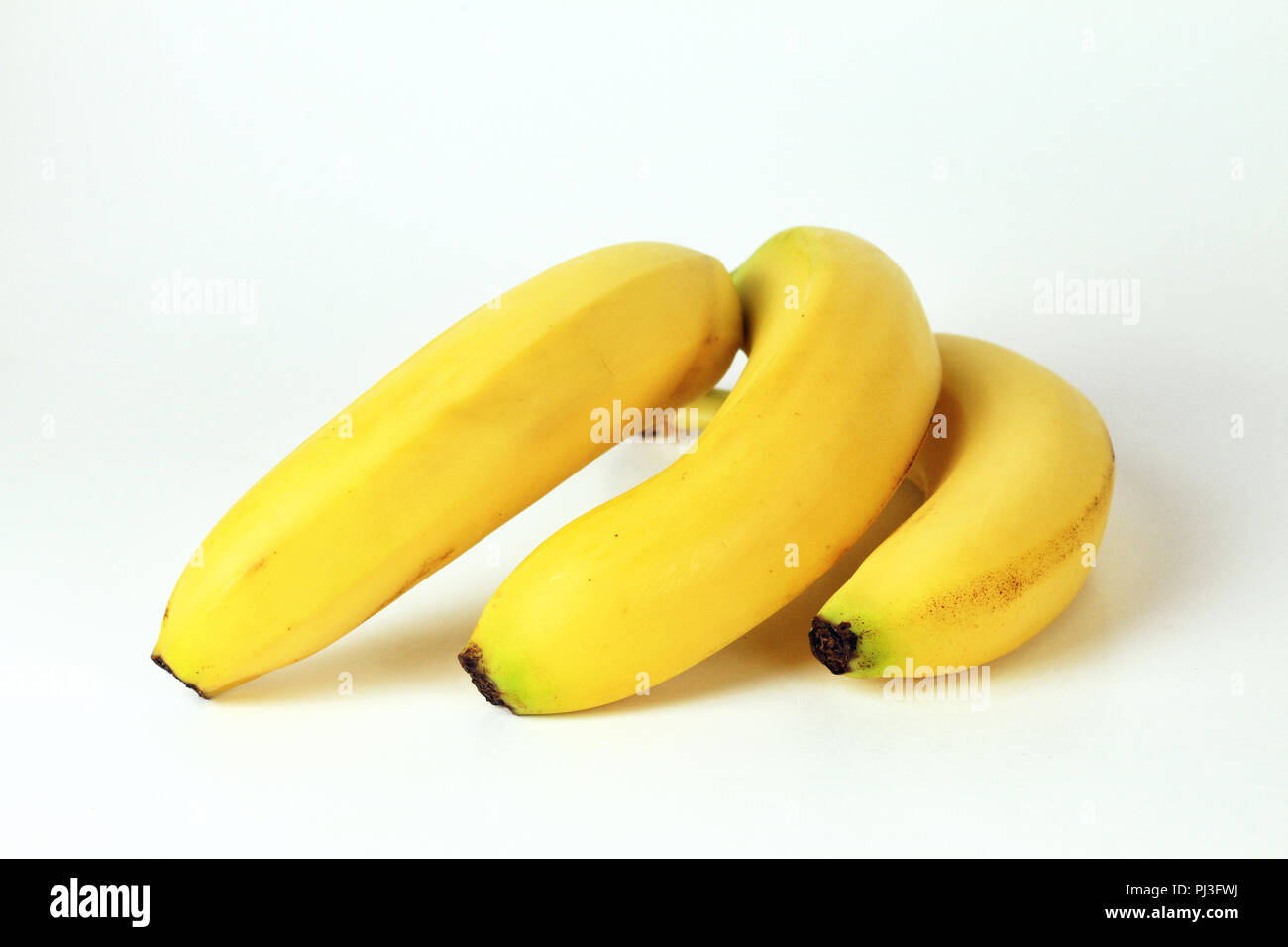 Un gruppo di tre gialli banane Cavendish resto a faccia in giù su uno sfondo bianco. Foto Stock
