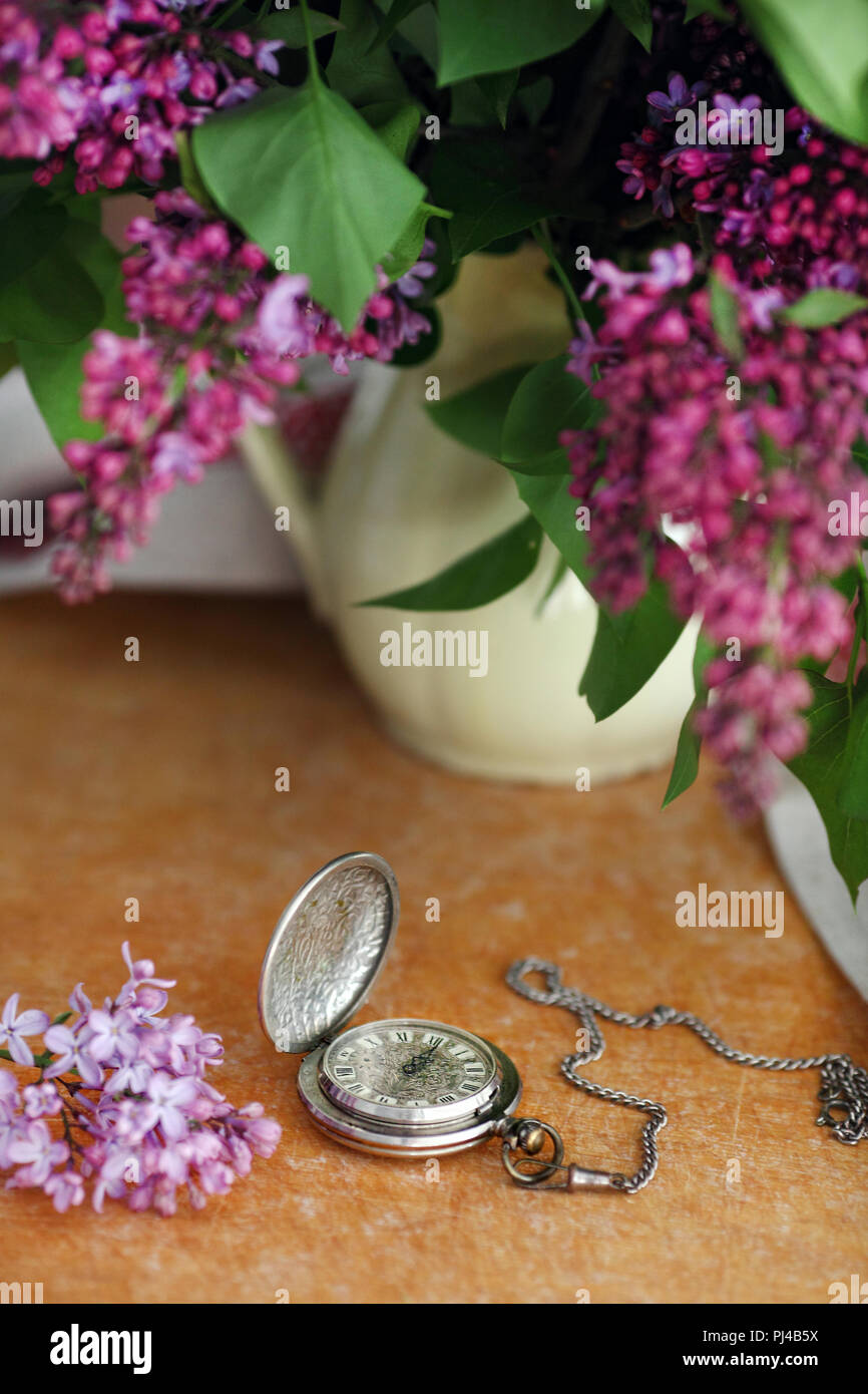 Antico orologio da tasca, fiore di fronte a sfondo di legno Foto Stock
