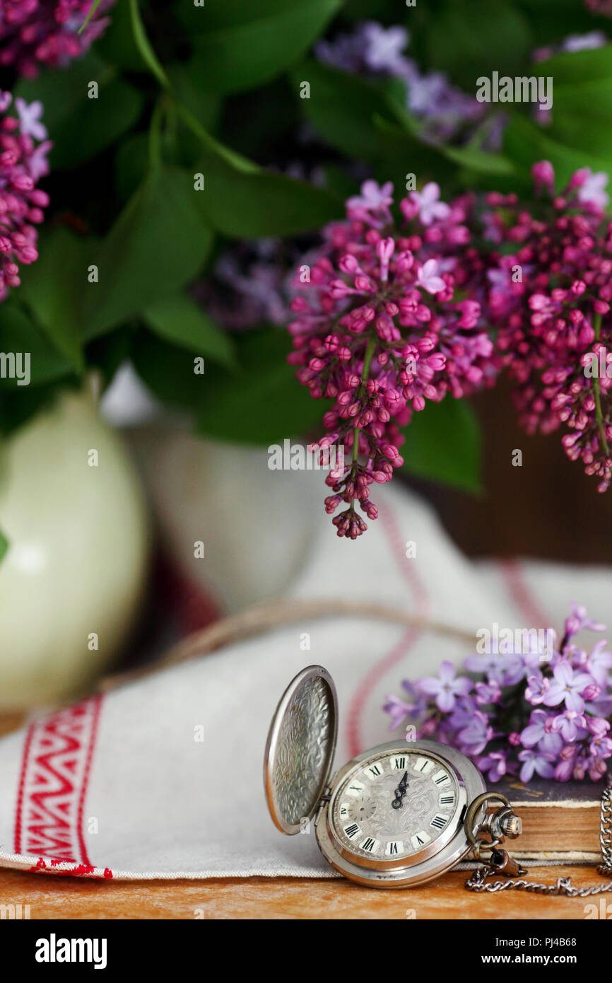 Antico orologio da tasca su uno sfondo di legno, con fiori lilla Foto Stock