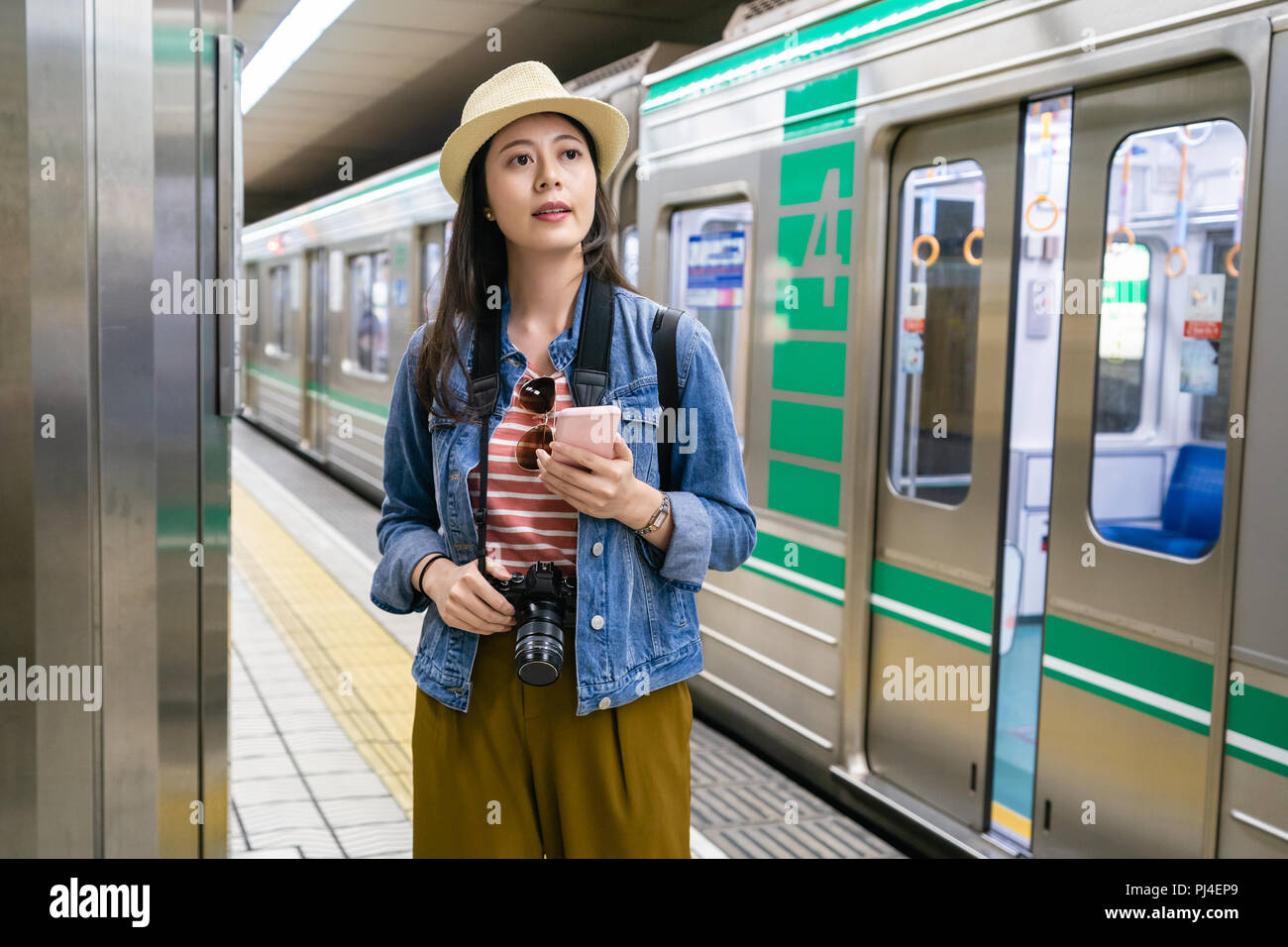 Carino buon viaggio ragazza con un telefono cellulare e di scendere dal treno per poi cercare di capire dove sta andando. Foto Stock