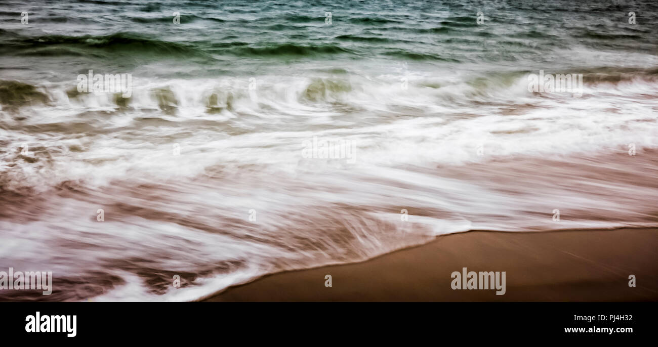 Movimento artistico di sfocare lo sfondo di La schiuma delle onde che lavare fino sulla spiaggia Foto Stock