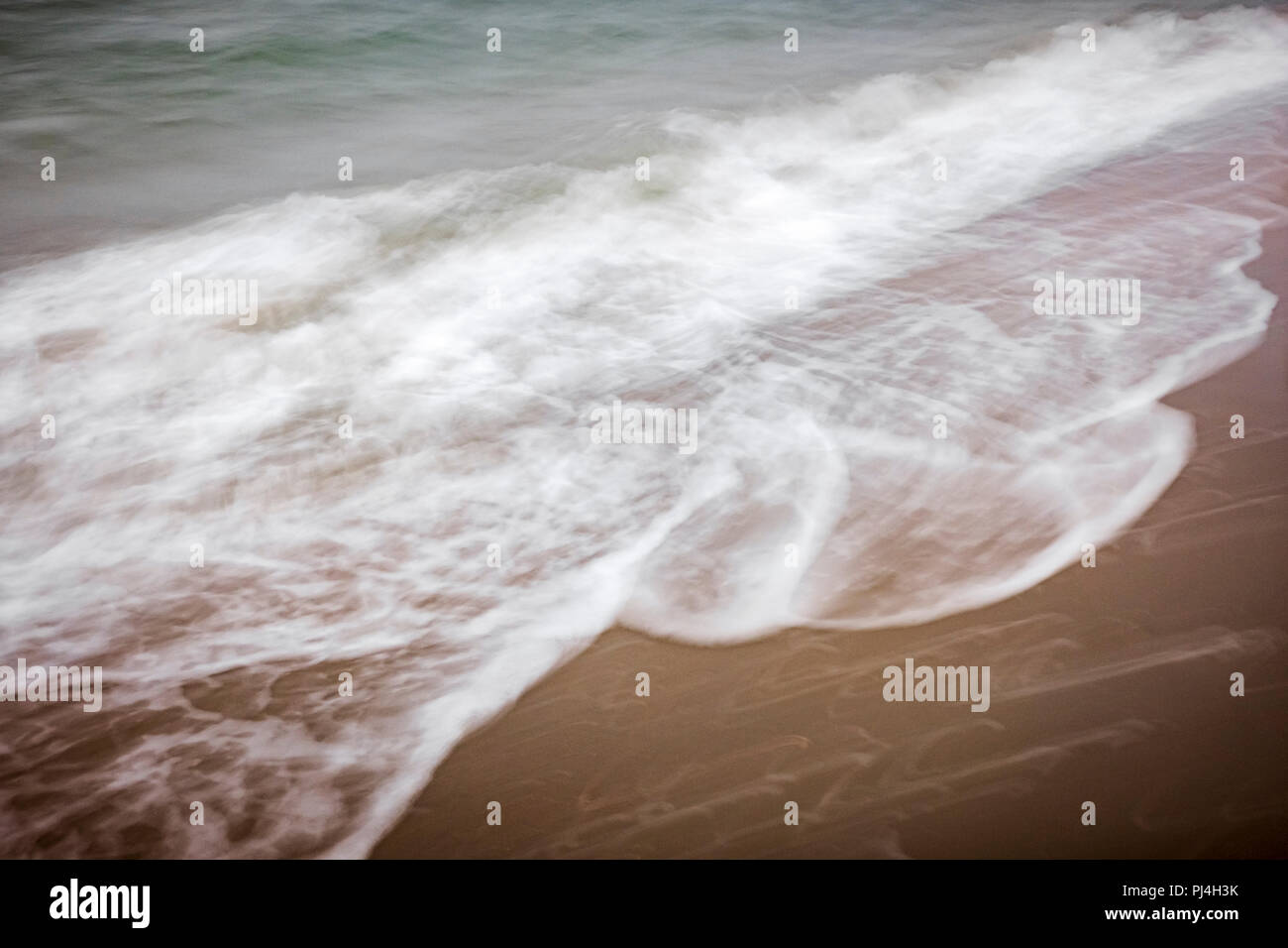 Movimento artistico di sfocare lo sfondo di La schiuma delle onde che lavare fino sulla spiaggia Foto Stock