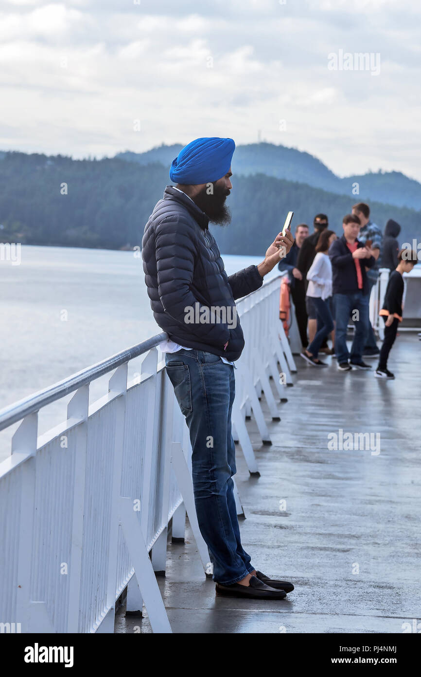 Passeggero in chalm con telefono sul ponte, traghetto, Vancouver, Victoria, Canada Foto Stock