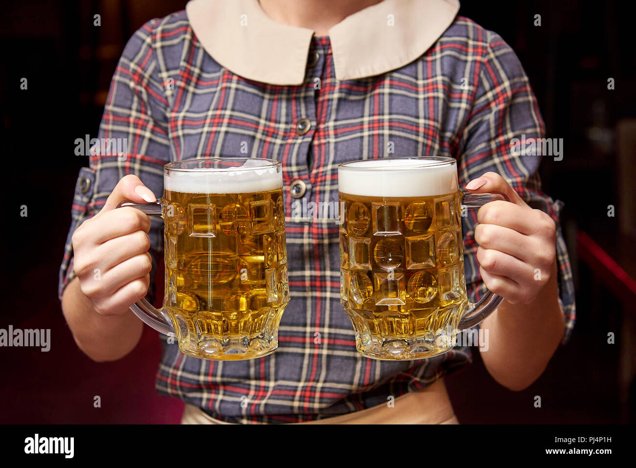 Due boccali di birra nelle mani del cameriere. Foto Stock