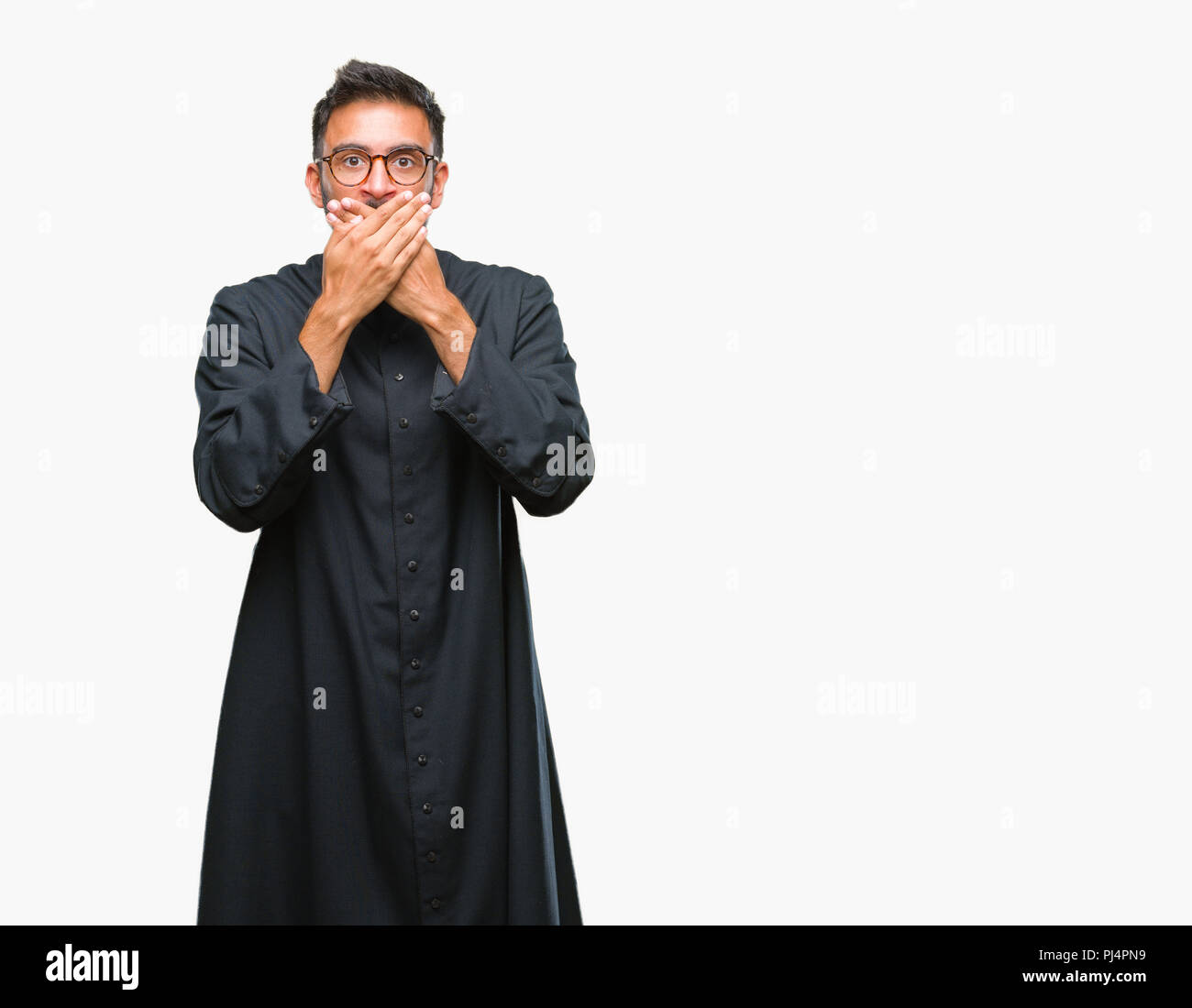Adulto ispanica sacerdote cattolico uomo su sfondo isolato scioccato che copre la bocca con le mani per errore. Concetto di segreto. Foto Stock
