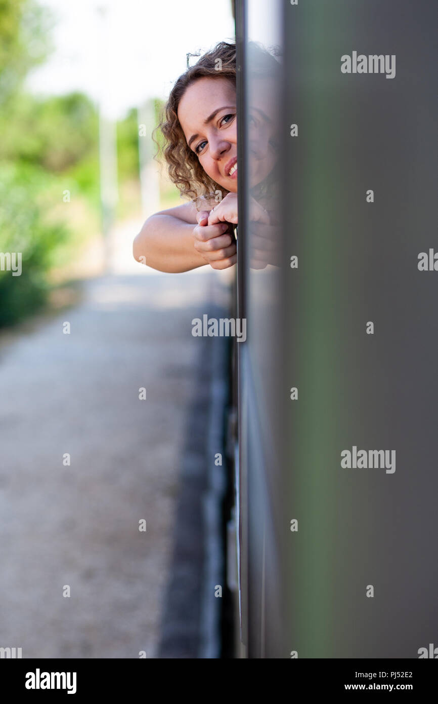 Sorridendo felice donna guarda fuori da una finestra del treno Foto Stock