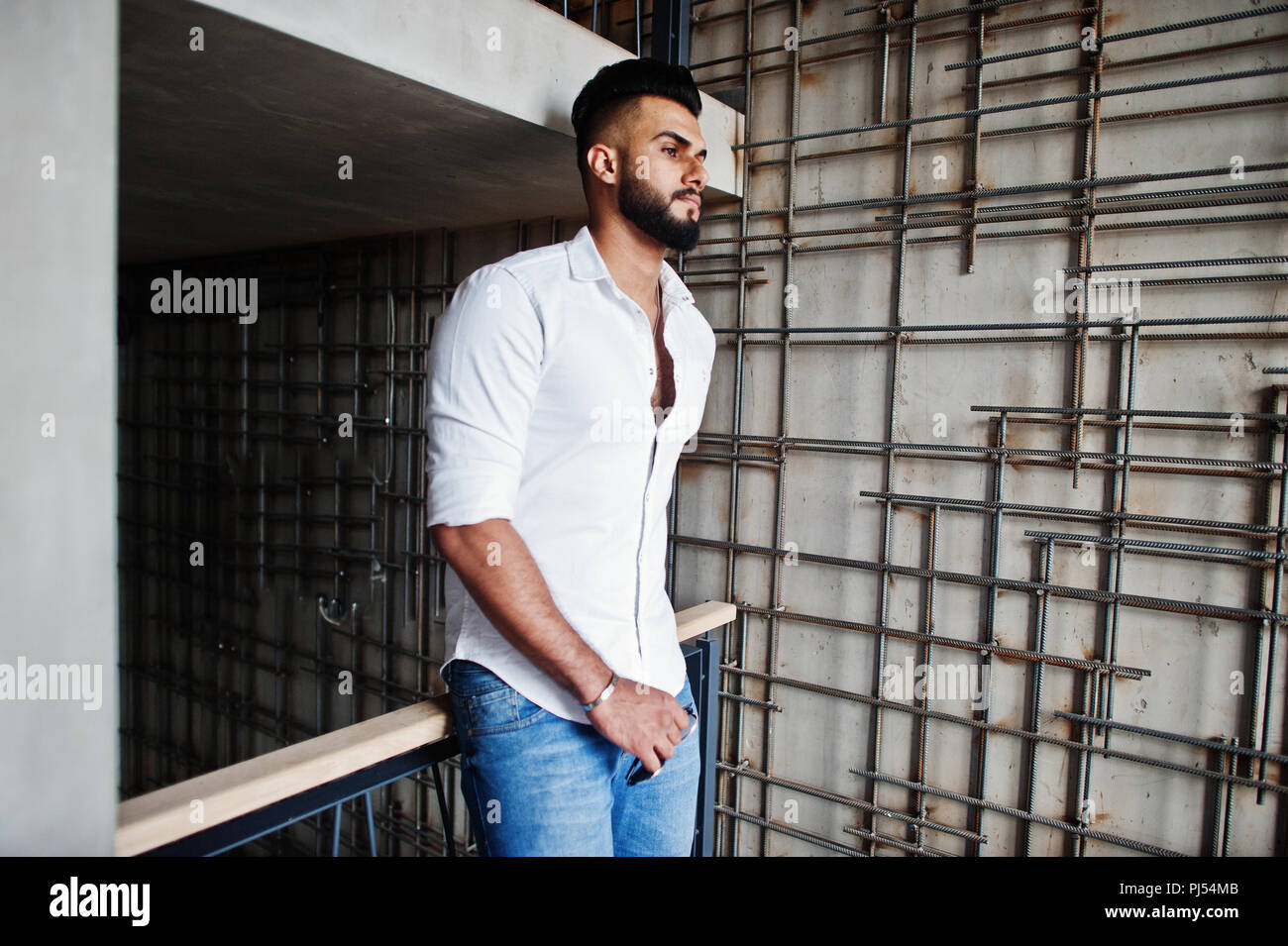 Elegante tall arabian modello da uomo in camicia bianca e jeans poste  contro la parete in acciaio indoor. Barba attraente ragazzo arabo Foto  stock - Alamy