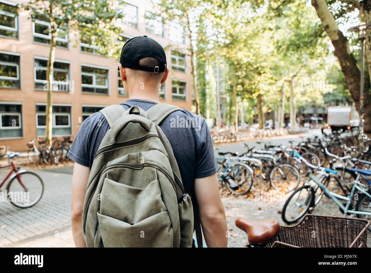 Uno studente con uno zaino o un turista su strada di Lipsia in Germania nei pressi del parcheggio per biciclette che si trova accanto alla biblioteca dell'Università di Leipig e ostello della gioventù. Foto Stock