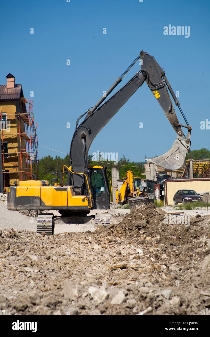 Un ferro di grandi dimensioni benna escavatore raccoglie e riversa macerie  di sabbia e pietre in una cava presso il cantiere per la costruzione della  strada strutture e case Foto stock -