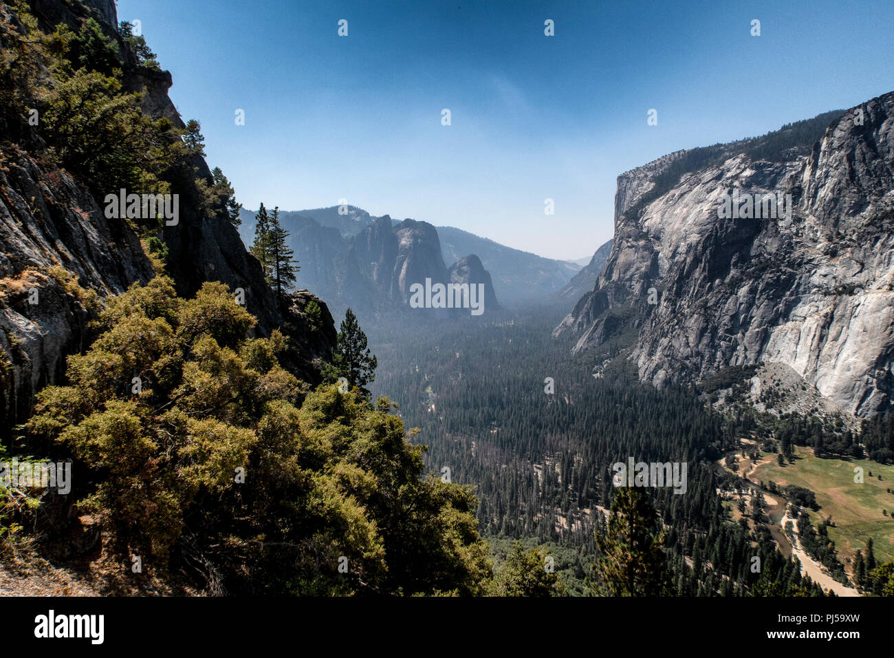 Una vista guardando verso il Parco Nazionale di Yosemite Valley con El Capitan sulla destra nel Parco Nazionale di Yosemite. Il fumo proveniente da incendi indugia nella valle. Foto Stock