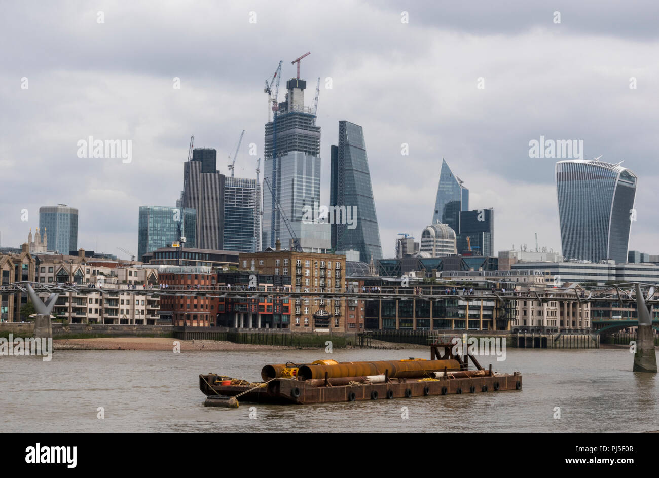 I componenti di costruzione su una chiatta sul fiume Tamigi nel centro di Londra con la City of London skyline di distanza. Foto Stock