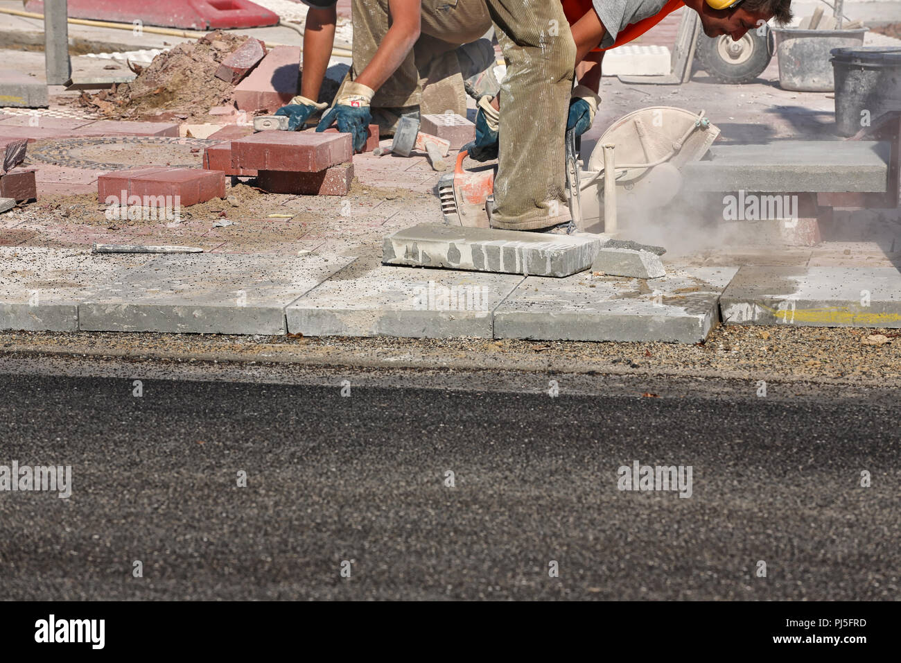 Lavoratore la posa di lastre in calcestruzzo sul marciapiede Foto Stock