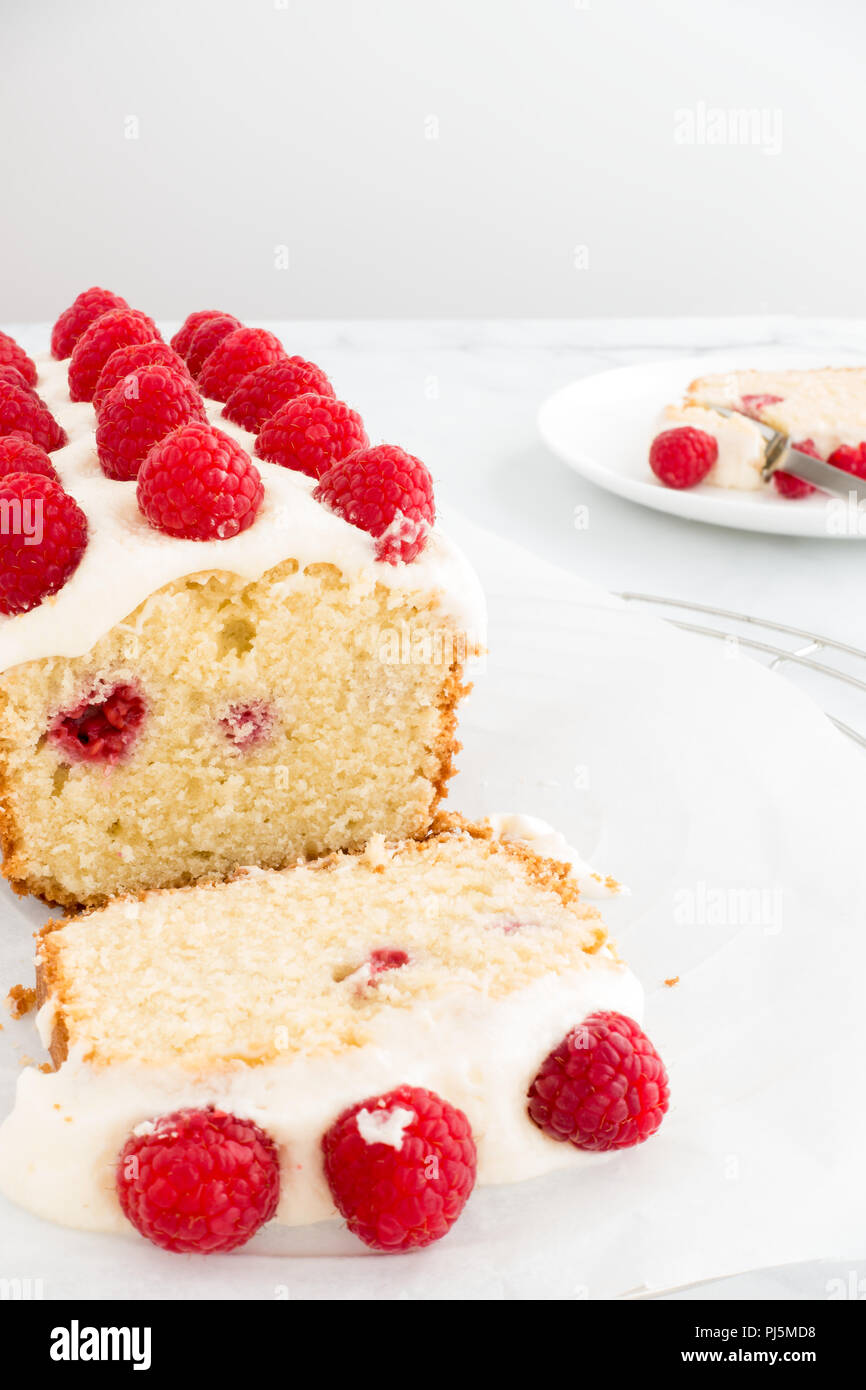 Primo piano di una casalinga lampone focaccia torta decorata con lamponi freschi su marmo bianco dello sfondo. Foto Stock