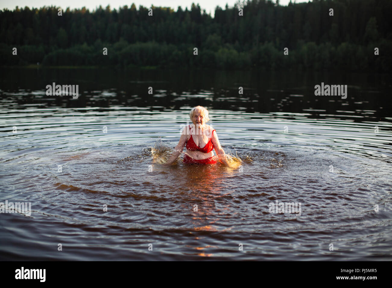 Donna anziana schizzi in estate fiume al tramonto. Foto Stock