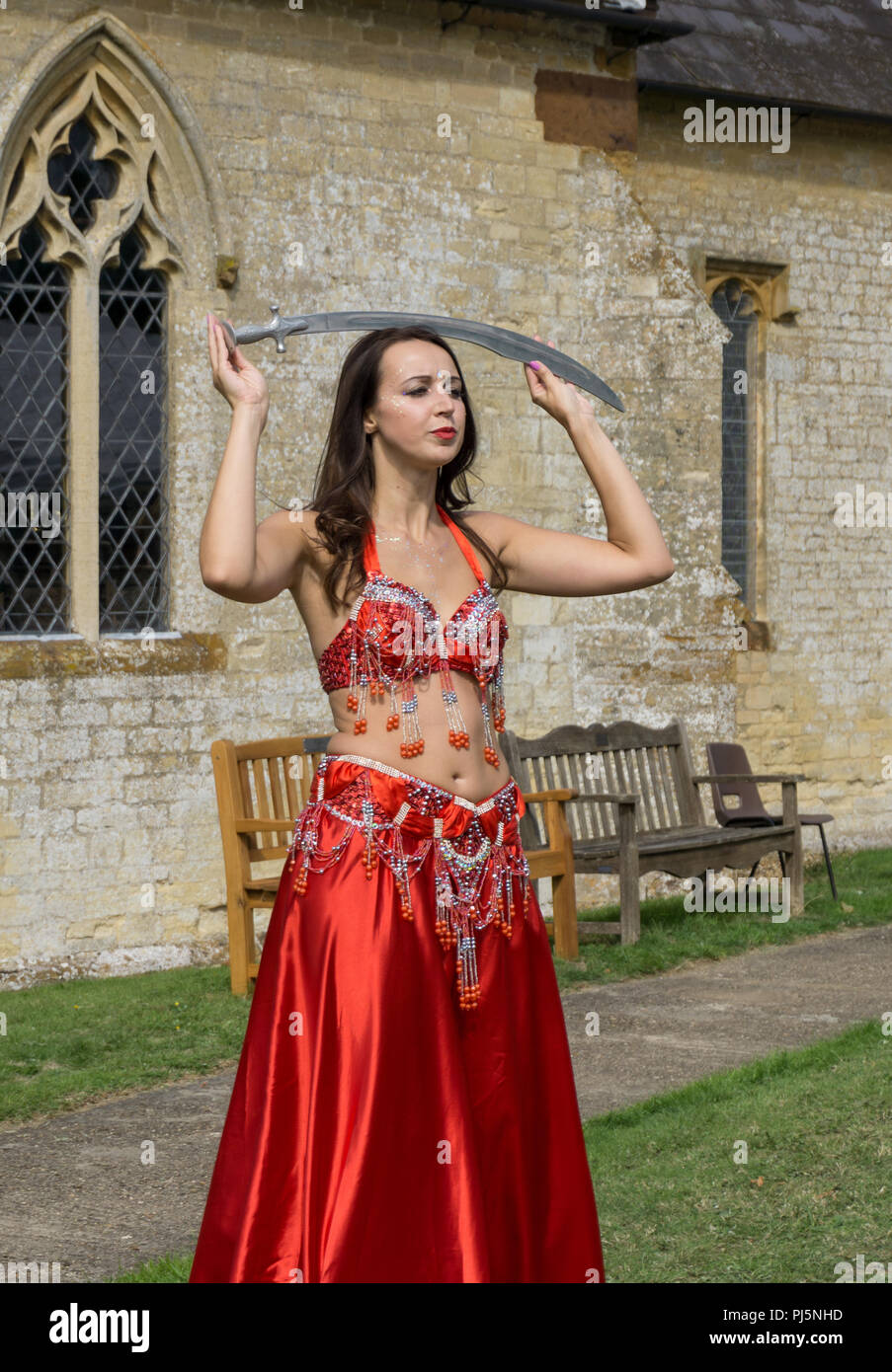 Una danzatrice del ventre, in costume tradizionale, eseguendo una danza con un sabre al a Alderton Arts Festival, Northamptonshire, Regno Unito Foto Stock