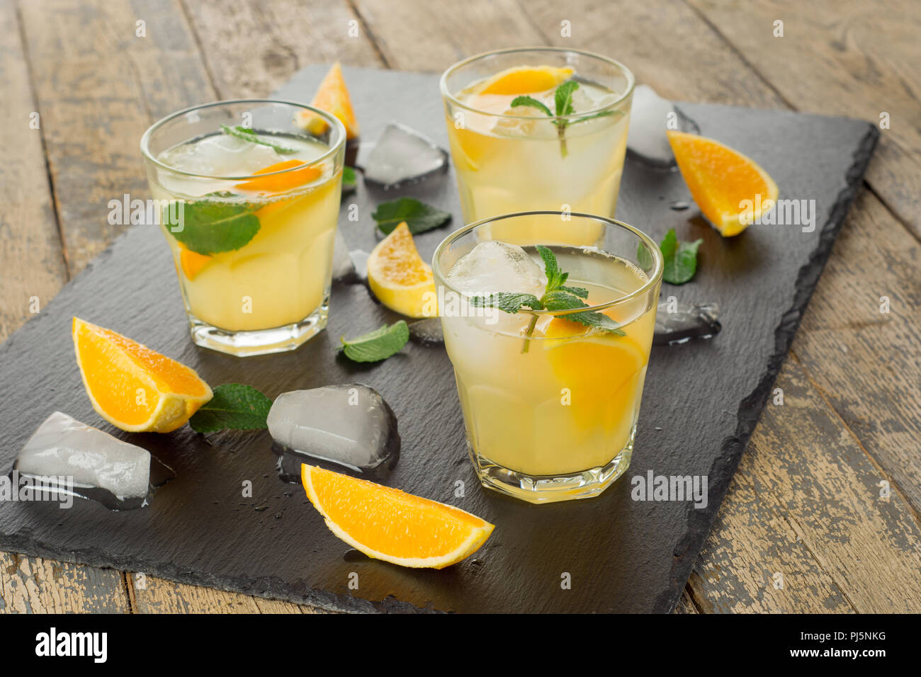 Cocktail. Succo di arancia con la menta e il ghiaccio su tavola in legno rustico Foto Stock