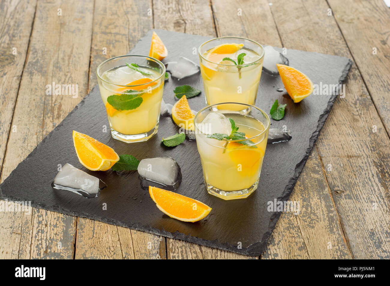 Cocktail. Succo di arancia con la menta e il ghiaccio su tavola in legno rustico Foto Stock