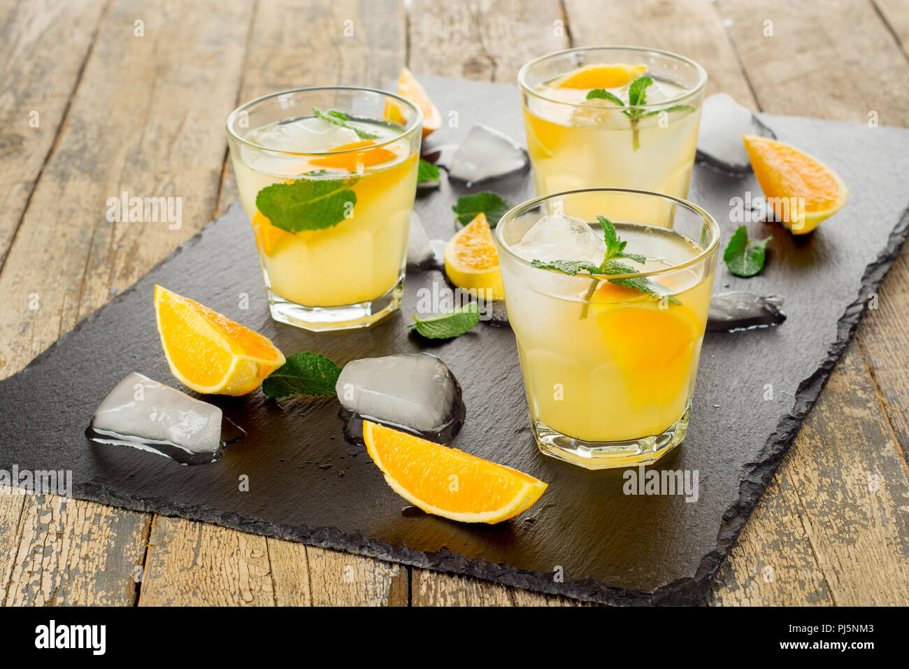 Bevanda estiva. Citrus limonata con la menta e il ghiaccio sul bianco sullo sfondo di legno. Foto Stock