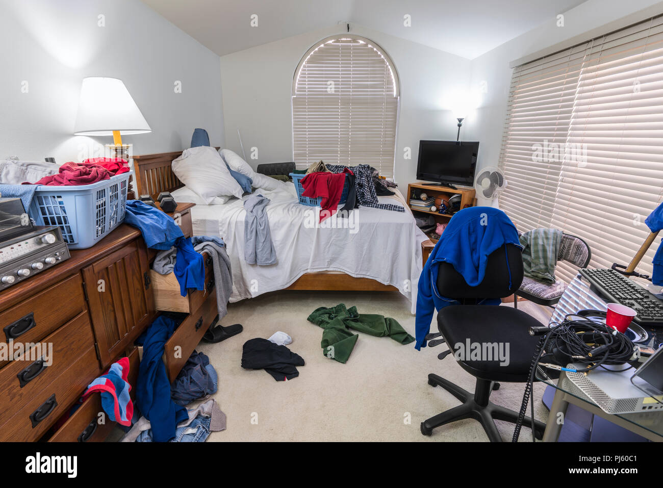 Di disordine, ingombra di ragazzo adolescente la camera da letto con pile di vestiti, musica e attrezzature sportive. Foto Stock